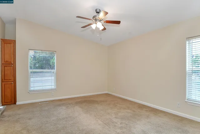 an empty room with windows and fan