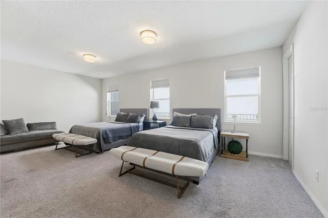a bedroom with a bed a couch and a flat tv screen