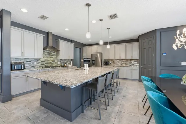 a kitchen with stainless steel appliances kitchen island granite countertop a table chairs and a refrigerator