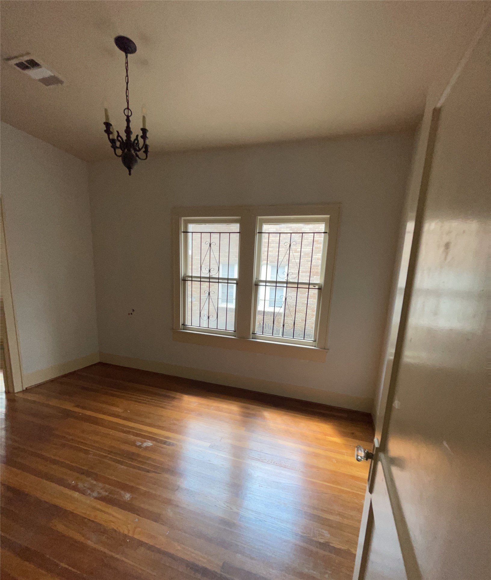 4716 Crawford Street Houston, TX 77004 - Photo 8 of 14 an empty room with wooden floor chandelier and windows