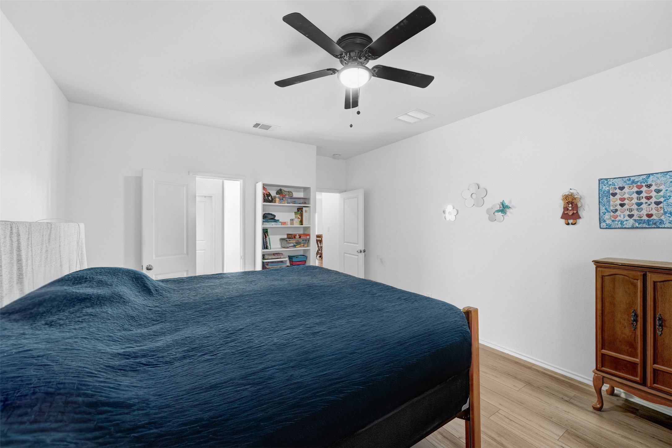 413 Perfect World Loop Jarrell, TX 76537 - Photo 17 of 39 Well-lit sleeping quarters with a ceiling fan, a built-in bookshelf, and light wood-tone flooring.