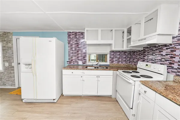 a kitchen with granite countertop a sink stove and refrigerator