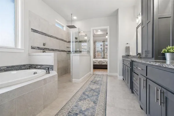 a bathroom with a granite countertop tub sink shower and mirror