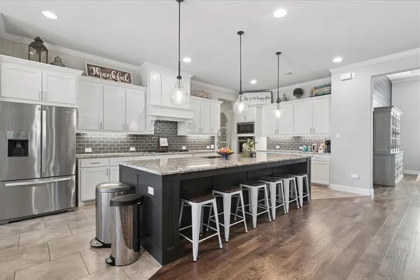 a kitchen with stainless steel appliances granite countertop a sink a stove a refrigerator and island with wooden floor