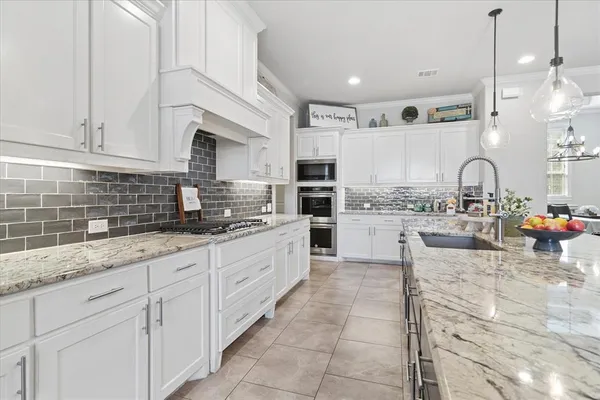a kitchen with kitchen island granite countertop a sink a counter top space appliances and cabinets