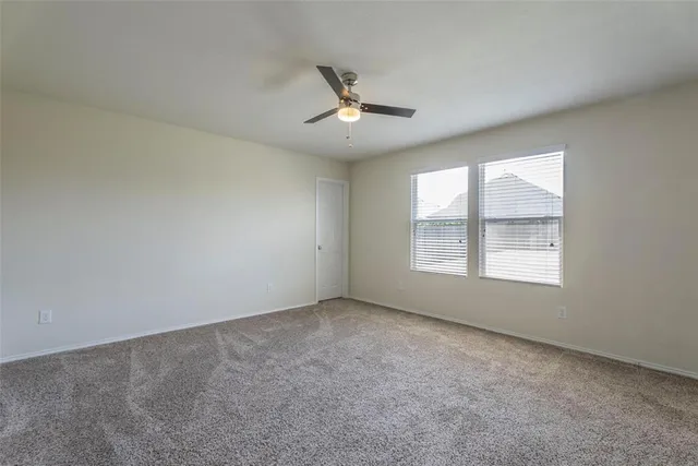 an empty room with a window and ceiling fan