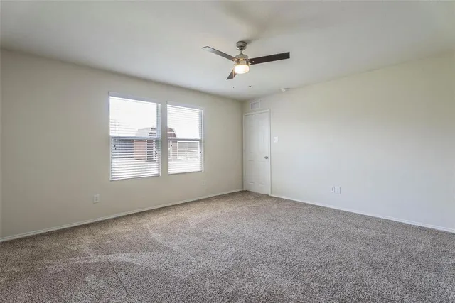 an empty room with a window and a ceiling fan