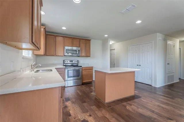a kitchen with stainless steel appliances granite countertop a sink a stove top oven a counter space and cabinets