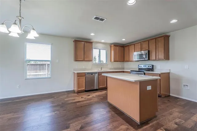 a large kitchen with stainless steel appliances granite countertop a stove a sink a refrigerator and a wooden cabinets