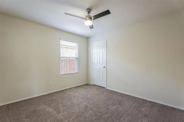an empty room with a ceiling fan and windows
