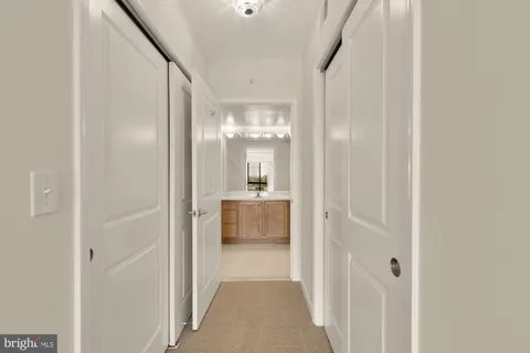 a view of a hallway with wooden floor and a bathroom