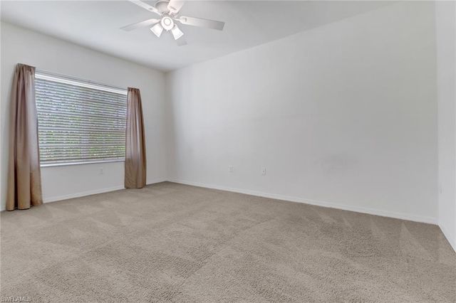 an empty room with chandelier fan and windows