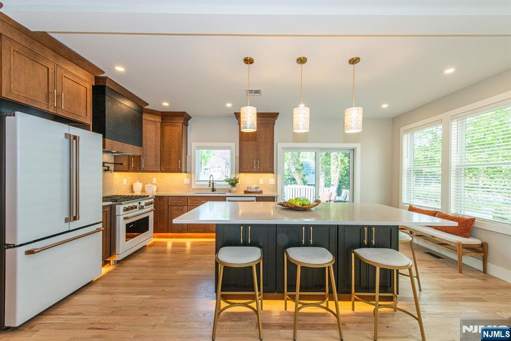 43 Alexander Avenue Montclair, NJ 07043 - Photo 11 of 50 a kitchen with stainless steel appliances granite countertop a stove top oven a sink dishwasher a dining table and chairs with wooden floor