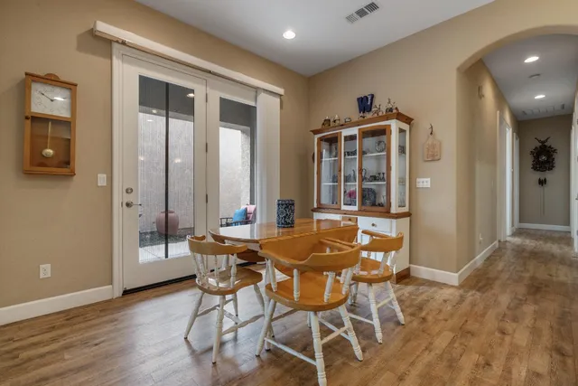 a kitchen with stainless steel appliances granite countertop wooden cabinets a sink a stove a dining table and chairs