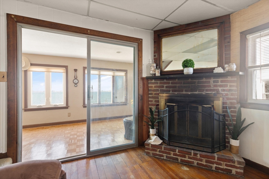 55 Castle Road Nahant, MA 01908 - Photo 13 of 32 a living room with a fireplace and a floor to ceiling window