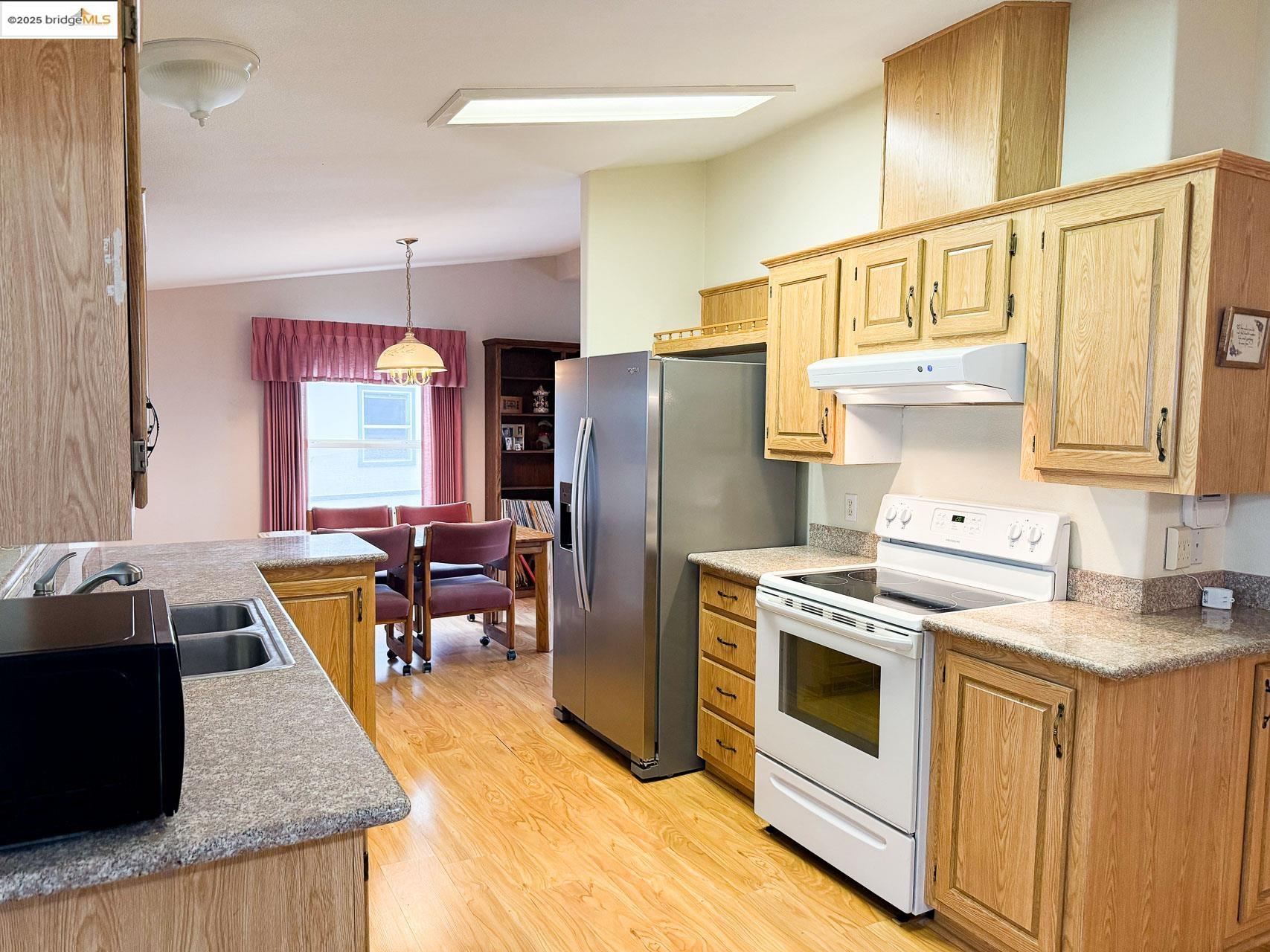 18717 Mill Villa Road, Unit 636 Jamestown, CA 95327 - Photo 13 of 24 a kitchen with stainless steel appliances granite countertop a refrigerator a stove a sink dishwasher and white cabinets with wooden floor