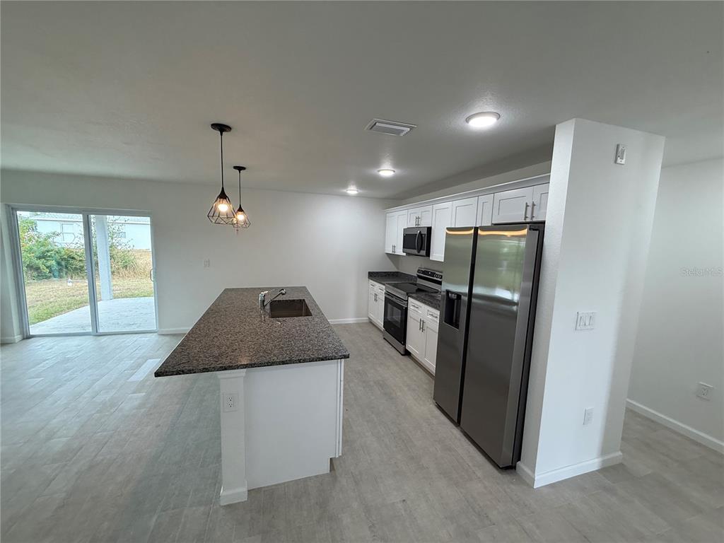 2164 Northland Avenue North Port, FL 34288 - Photo 4 of 31 a kitchen with stainless steel appliances granite countertop a refrigerator a sink a stove and a refrigerator with wooden floor