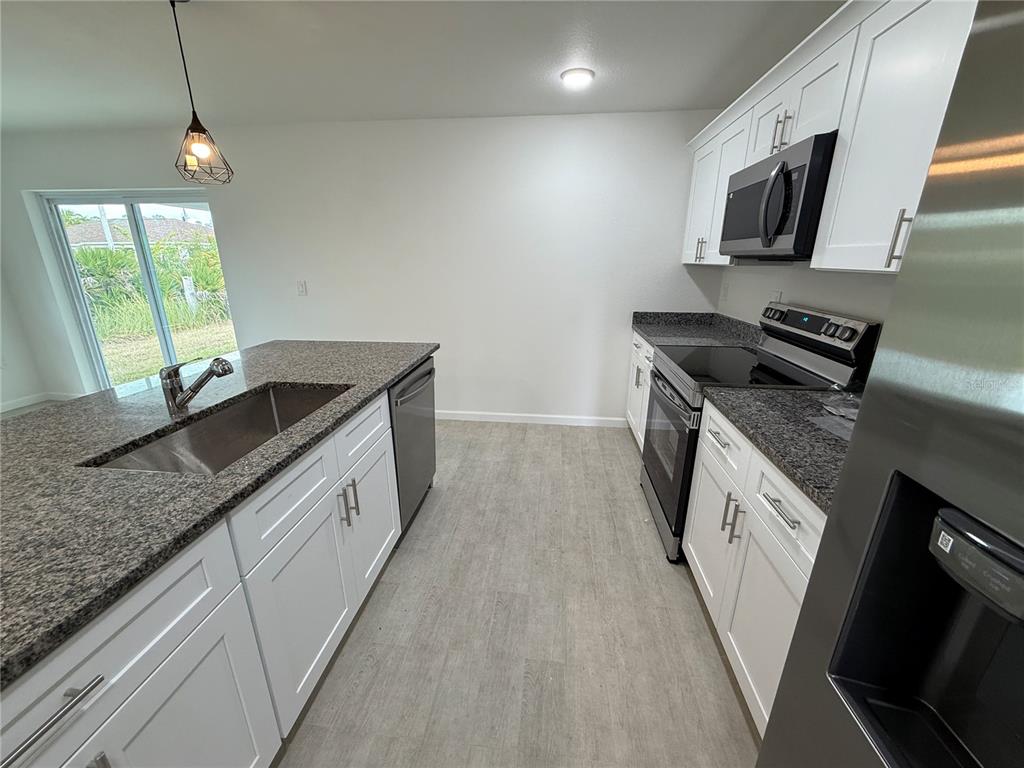 2164 Northland Avenue North Port, FL 34288 - Photo 5 of 31 a kitchen with granite countertop a sink stove and cabinets