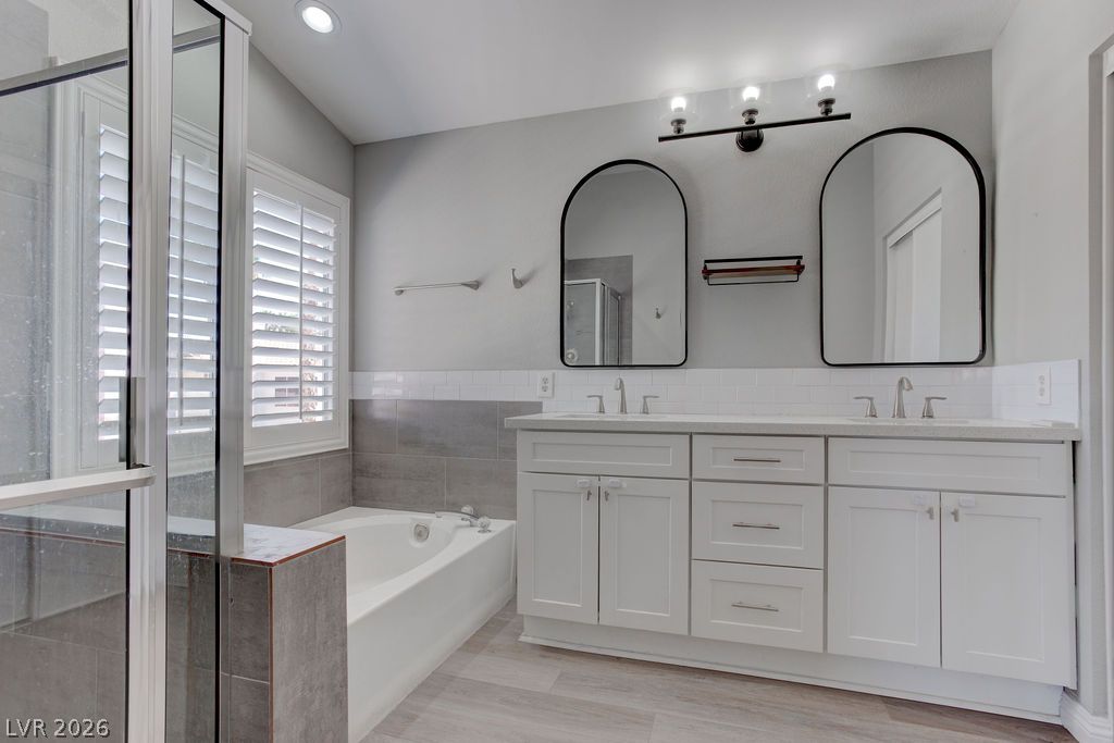 1416 Walstone Road North Las Vegas, NV 89031 - Photo 37 of 47 Dual vanities with elegant mirrors and a soaking tub offer a serene bathroom retreat.
