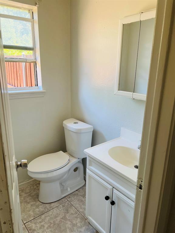 6320 Midway Road, Unit C Springtown, TX 76082 - Photo 6 of 11 Bathroom featuring a white vanity with cabinet storage, a white sink, and a white toilet