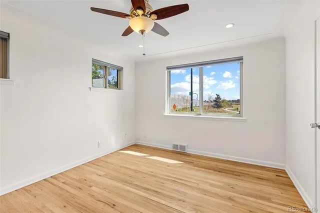 a view of empty room with wooden floor and fan