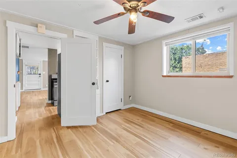a view of empty room with wooden floor and fan