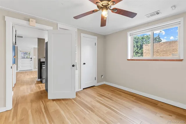 a view of empty room with wooden floor and fan