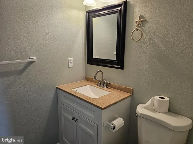 a bathroom with a toilet sink vanity and mirror
