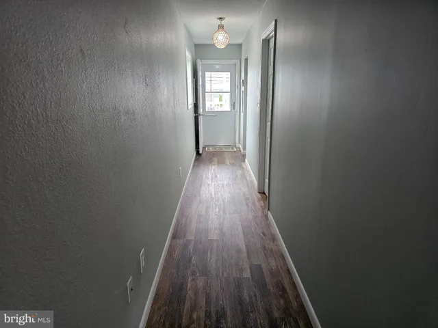 a view of a hallway with wooden floor and a mirror