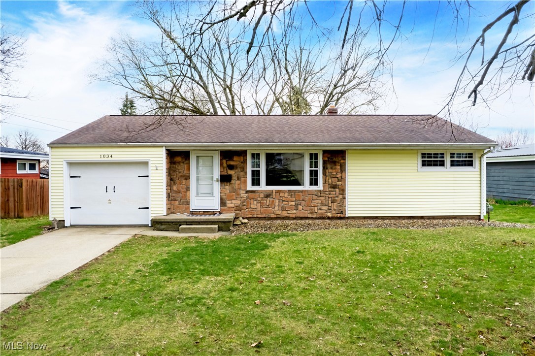1034 Ridgecrest Drive Wooster, OH 44691 - Photo 1 of 20 Ranch-style house featuring a front yard, stone siding, concrete driveway, fence, and an attached garage