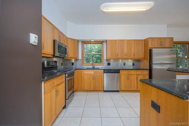 a large kitchen with stainless steel appliances kitchen island granite countertop a sink counter space and a view of living room