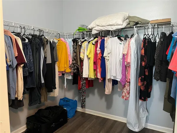 a walk in closet with clothes and shoes