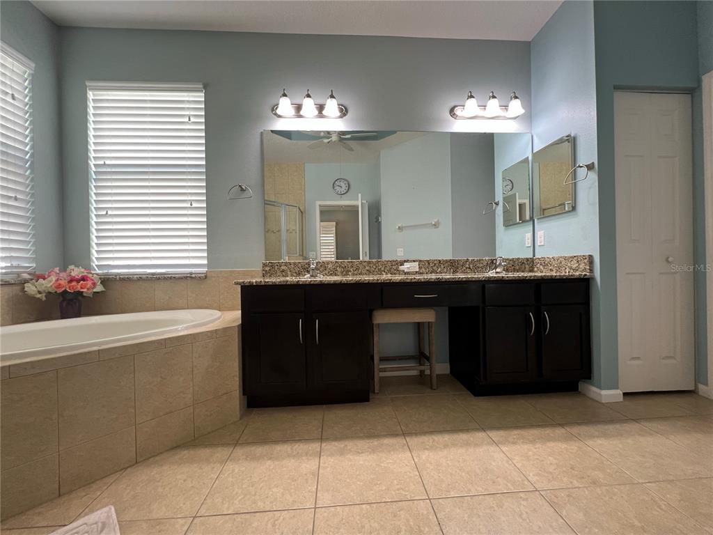 4419 Azure Isle Way Kissimmee, FL 34744 - Photo 22 of 39 a bathroom with a granite countertop double vanity sink a mirror and a bathtub