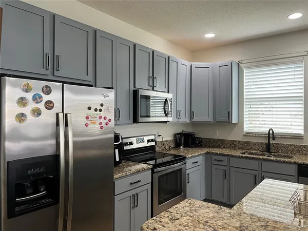 a kitchen with granite countertop a refrigerator sink and stove