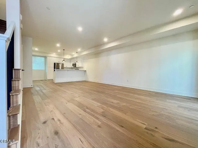 a kitchen with a refrigerator a stove top oven a kitchen island and couches with wooden floor