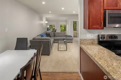 a living room with stainless steel appliances granite countertop furniture a microwave a sink and a stove