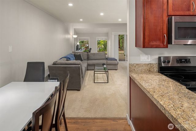 a living room with stainless steel appliances granite countertop furniture a microwave a sink and a stove