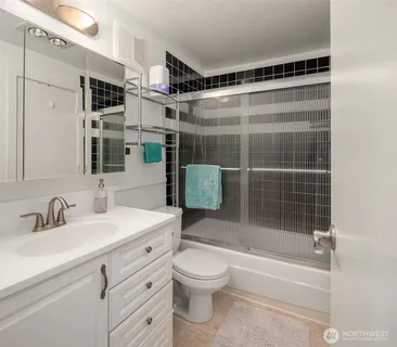 a bathroom with a shower sink vanity mirror and toilet
