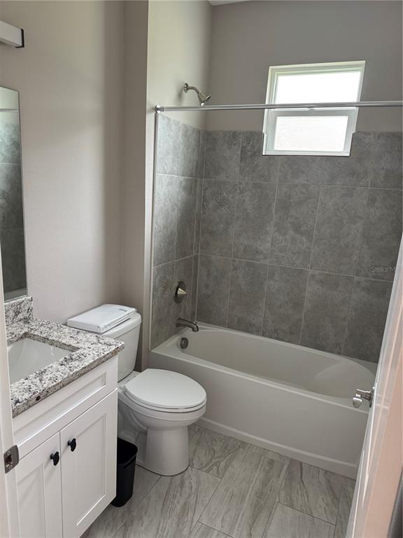 5238 2nd Street Orlando, FL 32810 - Photo 6 of 19 a bathroom with a granite countertop toilet a sink and bathtub