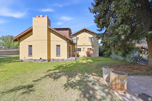 292 West 400 South Springville, UT 84663 - Photo 5 of 37 Expansive rear exterior featuring a two-story residence with a prominent chimney, a spacious lawn area, and mature trees providing shade