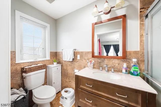 a bathroom with a granite countertop toilet sink and mirror