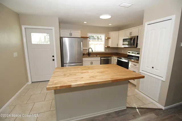 a kitchen with stainless steel appliances granite countertop a refrigerator oven a sink dishwasher and white cabinets with wooden floor