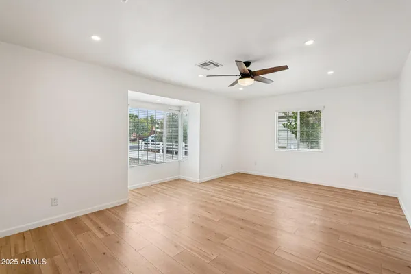an empty room with wooden floor fan and windows