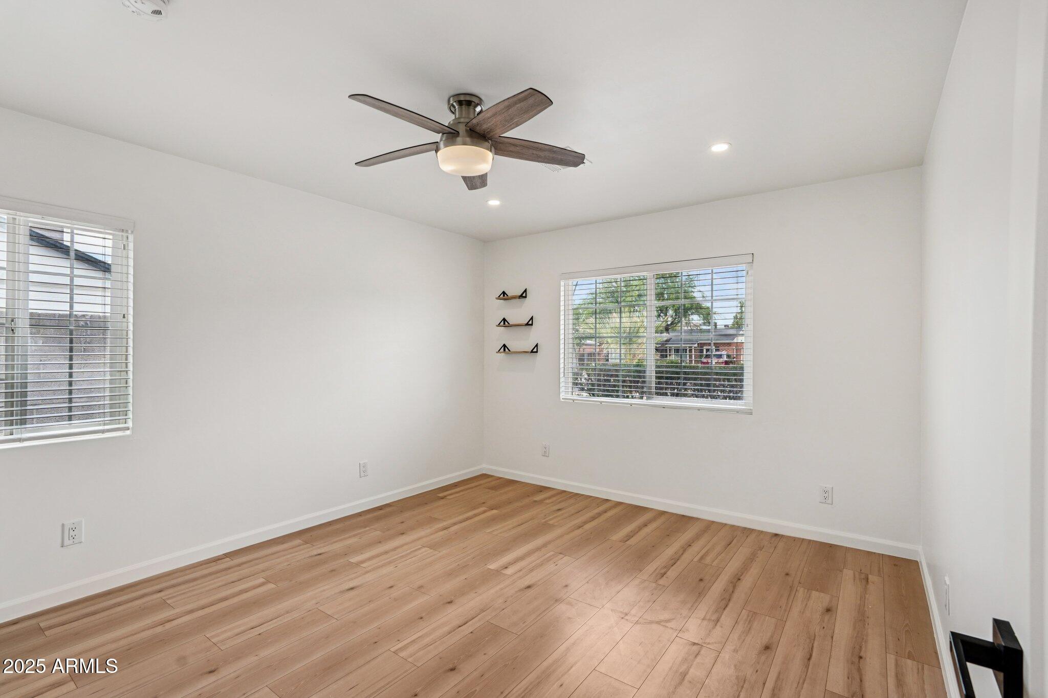 511 East Cheery Lynn Road Phoenix, AZ 85012 - Photo 12 of 33 an empty room with wooden floor fan and windows