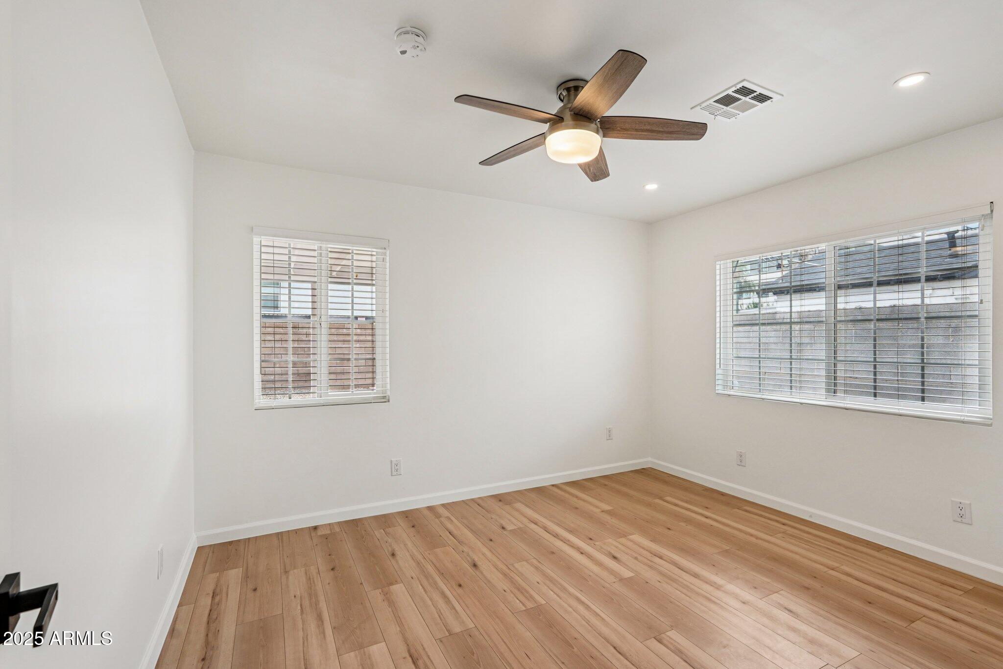 511 East Cheery Lynn Road Phoenix, AZ 85012 - Photo 18 of 33 an empty room with wooden floor fan and windows