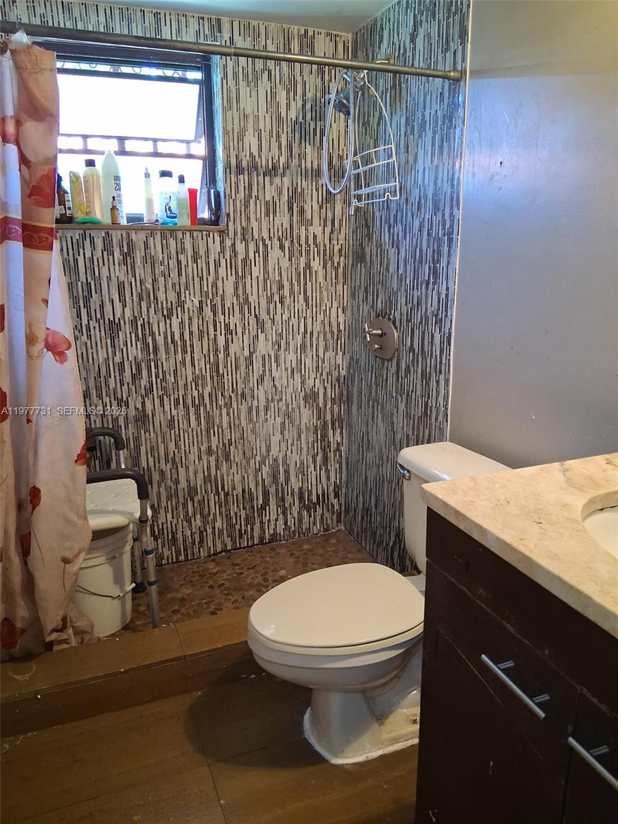 960 Southwest 13th Court Miami, FL 33135 - Photo 3 of 15 a white toilet sitting next to a shower curtain