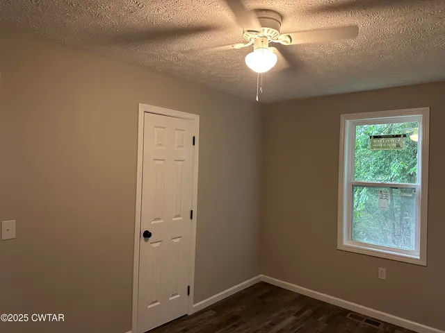 an empty room with windows and fan