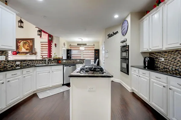a kitchen with stainless steel appliances a stove a sink and white cabinets