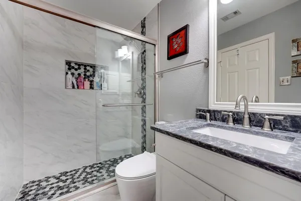 a bathroom with a granite countertop sink toilet and shower