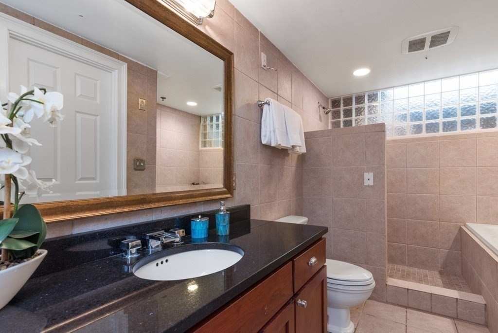 8 Howell Street, Unit 1 Boston, MA 02125 - Photo 11 of 14 a bathroom with a granite countertop sink toilet a mirror and shower
